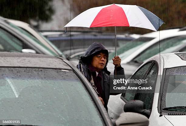 Maria Ubas makes her way to her car after attending church at Saint Euphrasia Catholic Church in Granda Hills during a rainstorm moving through the...