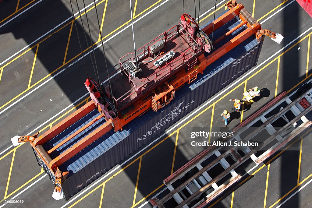 Crane Operator Loading A crane operator takes a container off a truck and loads it into the ...