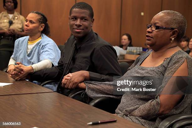 Fred Jingles holds the hand of his biological mother Kimberly Freeman and his adoptive mother, LaVetta White in Pasadena Juvenile Court during his...