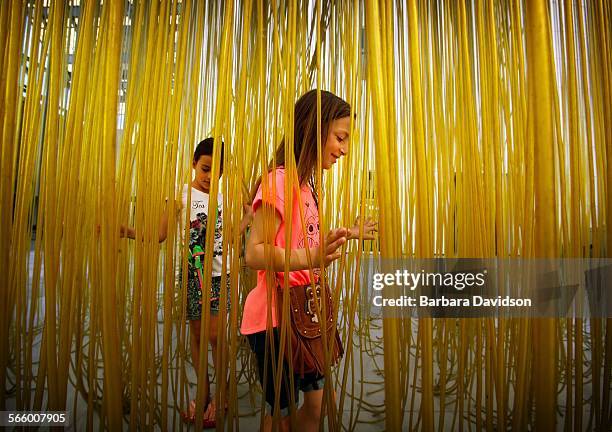 Seven-year-old Maya, , of LA, and her cousin, Anna of Arizona, walk through a maze of plastic hoses at LACMA Sept. 01, 2013 to pass the labor day...