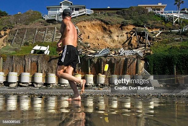 Jogger on Leucadia State Beach in Encinitas, CA looks up a bluff that collapsed below a house at 1500 Neptune Dr. The longtime home owner Barbara...