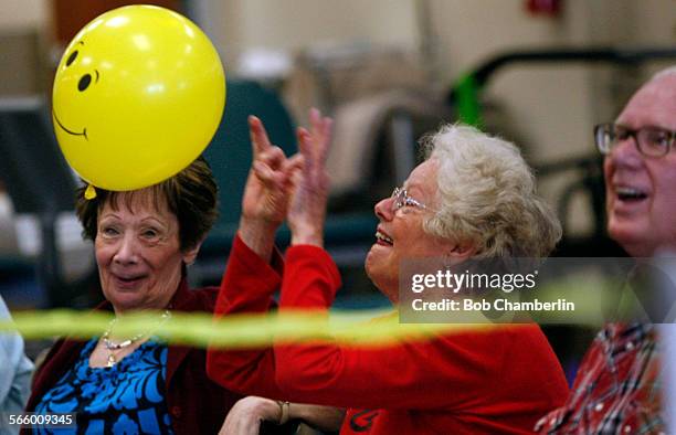 Veba Clark prepares to flick the smiley face yellow balloon over the net as baby boomers play Balloon Volleyball at Nifty after Fifty fitness center...