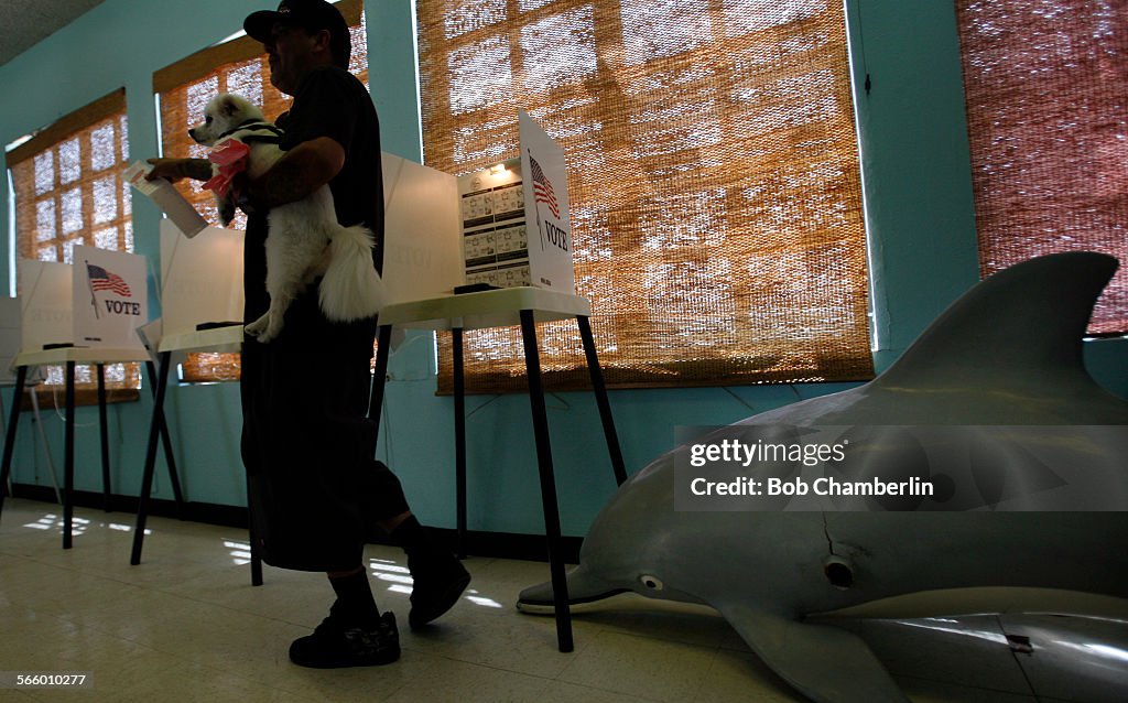 Paul Maes walks away from the polling booth to turn in his vote as he carries his dog Rocko next to