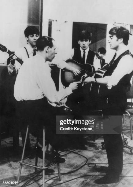 The Beatles at a recording session for the Parlophone label with their producer George Martin, circa 1963.