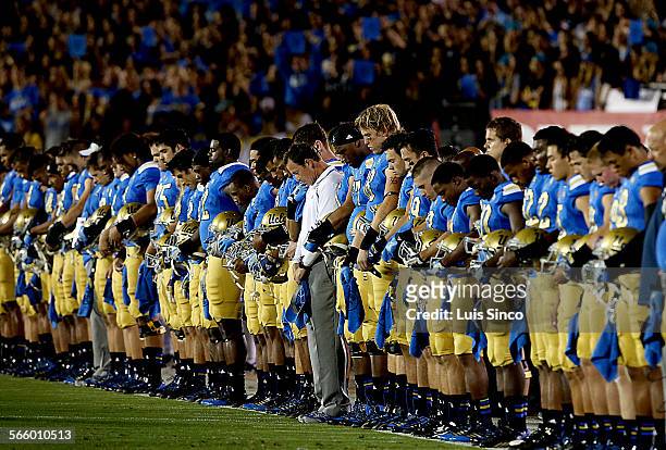 Coach Jim Mora and the UCLA Bruins football team observe a moment of silence in memory of teammate Nick Pasquale before the start of the game against...