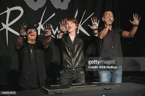 The Goo Goo Dolls display their hands after pressing them into cement during their inducted into Guitar Center's historic RockWalk.
