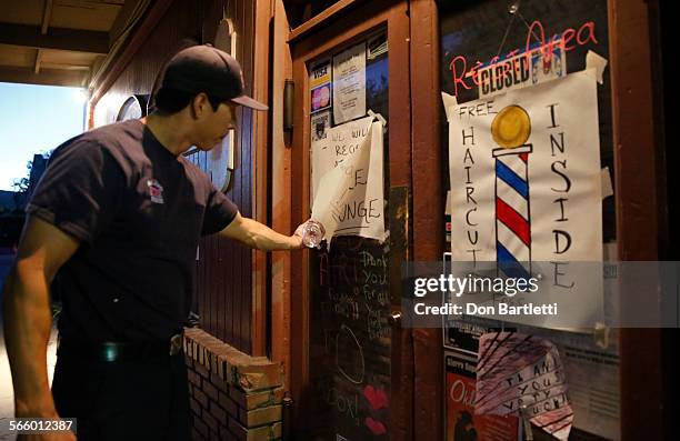 Vino Ornelas with the San Diego City fire department reads a note on the door of the Westside Ink tatoo business on Bay St in Tuolumne City, CA on...