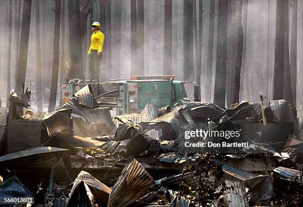 Firefighter surveys the smoldering ruins of The Berkeley Tuolumne Camp near Groveland, CA, on Aug 26, 2013. The 1922 village of cabins and a large...