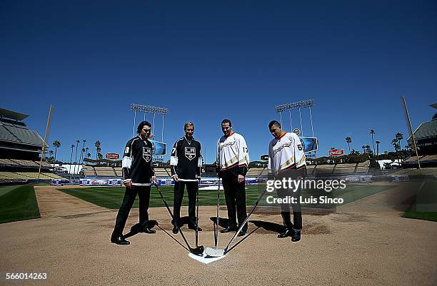 National Hockey League players Drew Doughty, left, Jeff Carter, Dustin Penner and Emerson Eten pose with their sticks at home plate following a press...