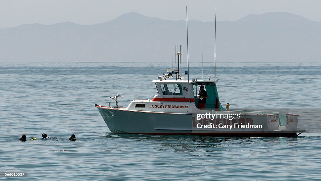 A lifeguard boat from the L.A.County Fire Department approaches three divers in the ocean hundreds