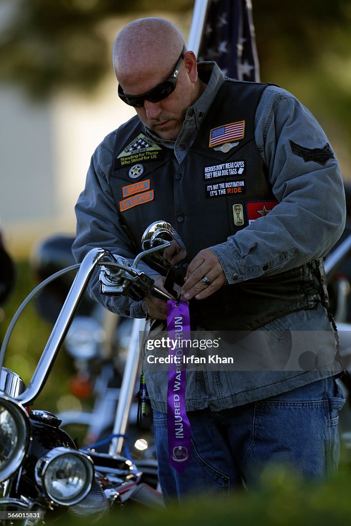 Pat Goodman ties a commemorative ribbon to his motorbike prior to a ride to Camp Pendleton to benef