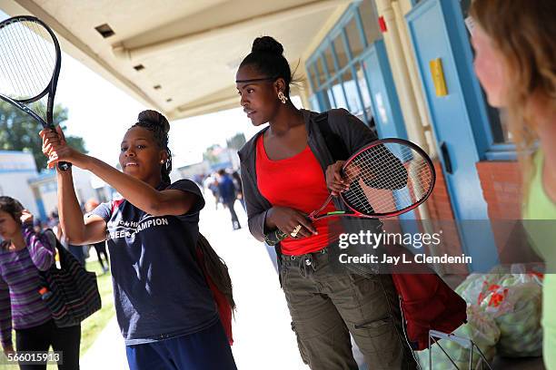 Tatiarria Hayes left, tries out a racquet with friend Robin Butler after sorting through tennis gear donated to their Compton High School team by...