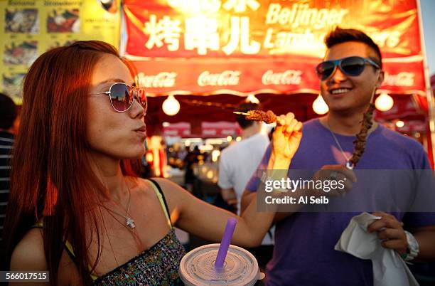 JeeHea So, left, with Matthew Tam, right, sample lamb skewers from "The Beijinger Lamb Skewers", at the Richmond Market packed on a Sunday night and...