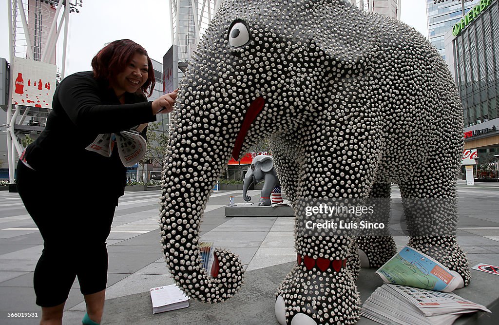 A passerby checks the texture of one of seven elephant statues set up in Nokia Plaza in downtown Lo
