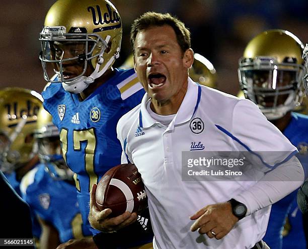 Head coach Jim Mora warms up with his team before the start of the game against the New Mexico State Aggies on Saturday, Sept. 21 at the Rose Bowl in...