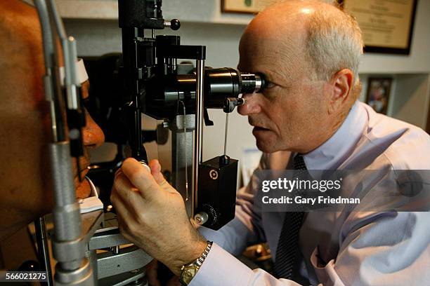 Robert Shapiro (right), Doctor of Optometry, examines a patient at..., News Photo