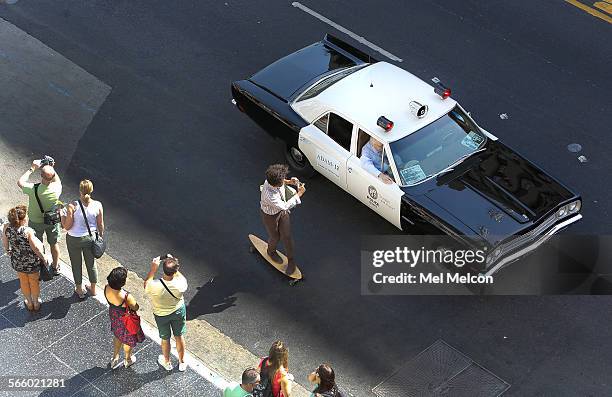 Skateboarder photographs a 1972 AMC Matador vehicle as it travels along Hollywood Blvd. In Hollywood during the annual 10-4 Day Parade, a salute to...