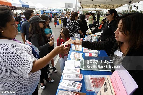 Martha Chehadi , of the Whittier Health Center from the Los Angeles County Department of Public Health, hands information to Socorro Guzman at the...