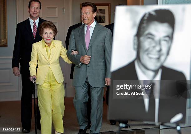 California Governor Arnold Schwarzenegger assists former first lady Nancy Reagan as they walk in for a ceremonial bill signing for SB 944 and AB 1911...