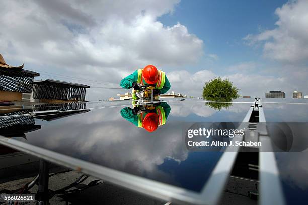 SolarCity Photovoltaics installer Victor Zapata uses a ban saw to make cuts while assembling thin film technology solar panels at the home of Andrew...
