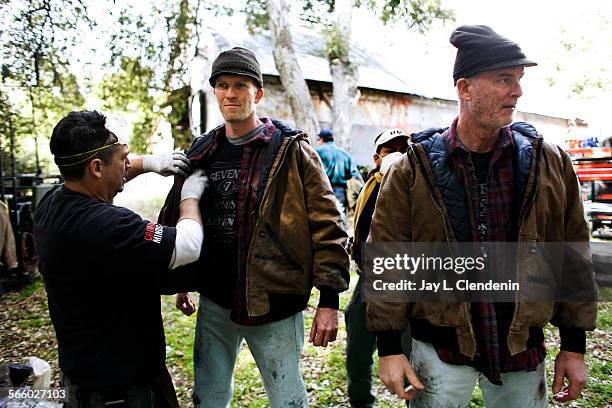 Stunt double Ian Eyre, left, is "soiled" by costumer James Spensley, along side actor Michael Shamus Wiles, before shooting a scene inside the...