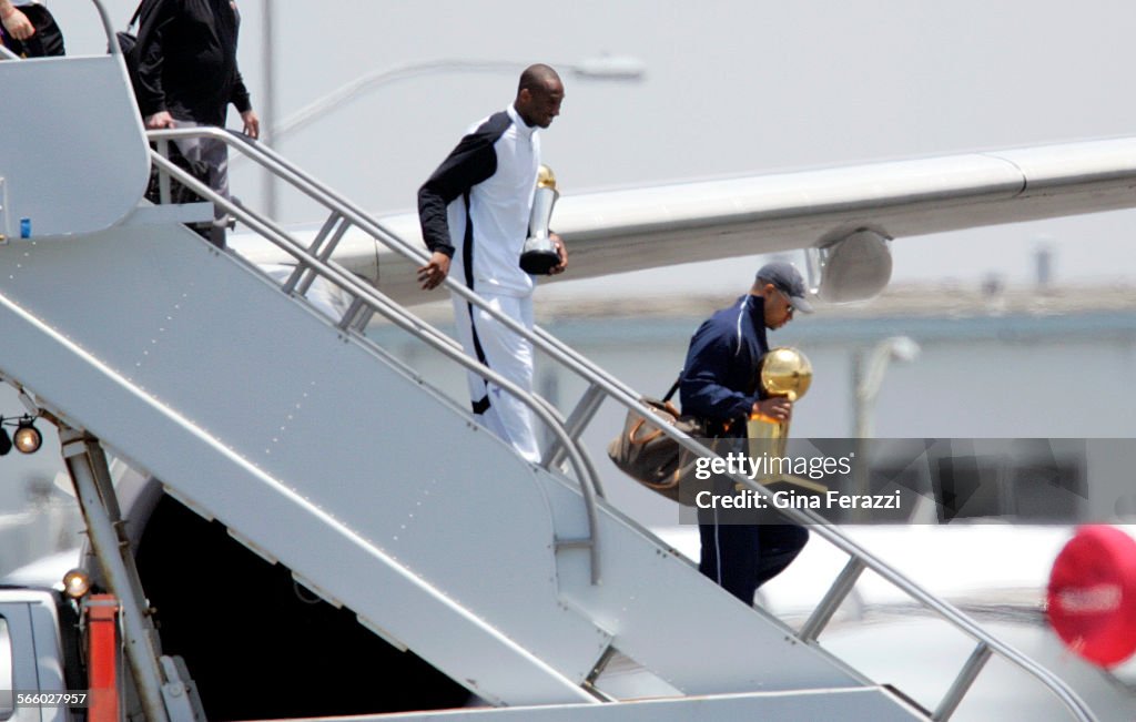 Lakers Kobe Bryant carries his MVP trophy as teammate Derek Fisher carries the championship trophy