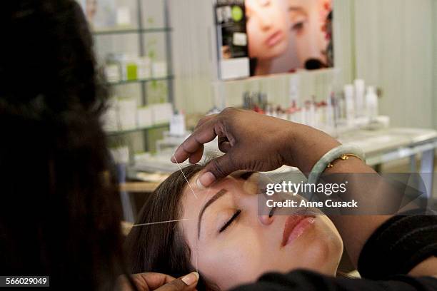 Beauty artist Nilofer Chariwala uses threading on the eyebrows of Stacie Negrete at Ziba Beauty, a threading salon, in Artesia on October 5, 2011....