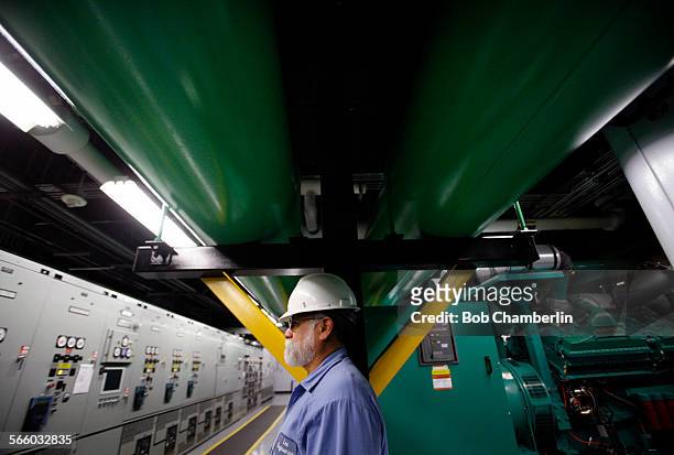 Engineer Lee Rodriguez monitors huge transformers, left, which turn on 16 cylinder engines, behind him, if there is a power failure at Garland Center...