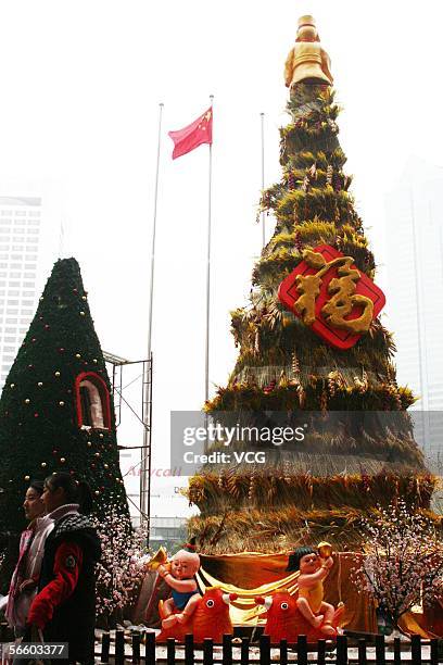 Two girls pose for photos in front of a tree which is part of a special show called horn of plenty displayed at a shopping mall on January 16, 2006...