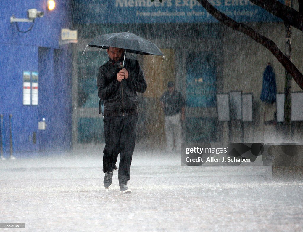 A man walks to his car from the Long Beach Aquarium during a heavy downpour in Long Beach. Southern