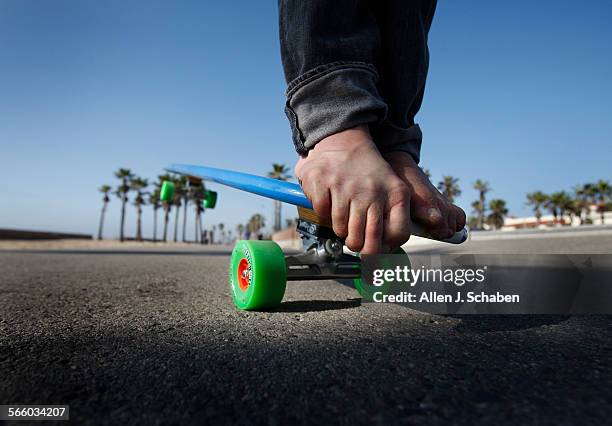 Gus Hamborg hangs ten, a move that complements his surfing style, on a 6'8" long Hamboard longboard skateboard along the Huntington Beach bike path....