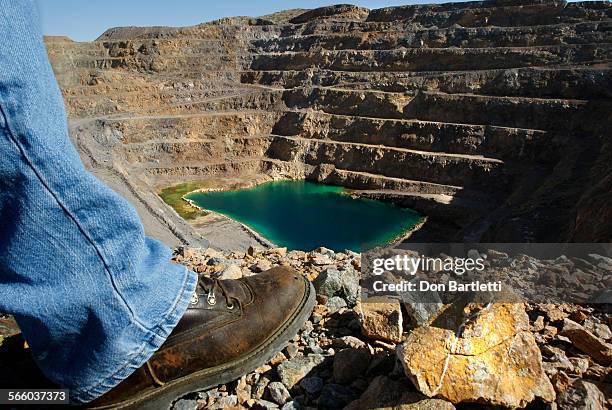 John Espinoza looks down on ground water that has accumulated in the pit of the Mountain Pass rare earth mine. Green sediment in the shallow...