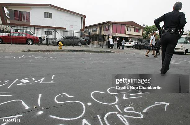 Officer walks on graffitti scarred Drew Street in front of two apartments that were targeted during a multi agency task force operation targeting the...