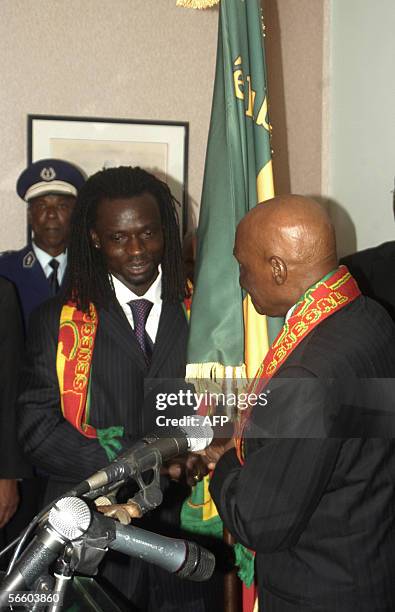 Senegalese President Abdoulaye Wade hands the national flag late 16 January 2006 to Teranga Lions player Ferdinand Coly in Dakar before the team's...