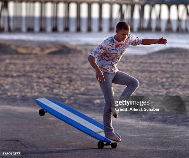 Anders Hamborg hangs five while crossing his legs, a move that complements his surfing style, on a 6'8" long Hamboard skateboard along the Huntington...