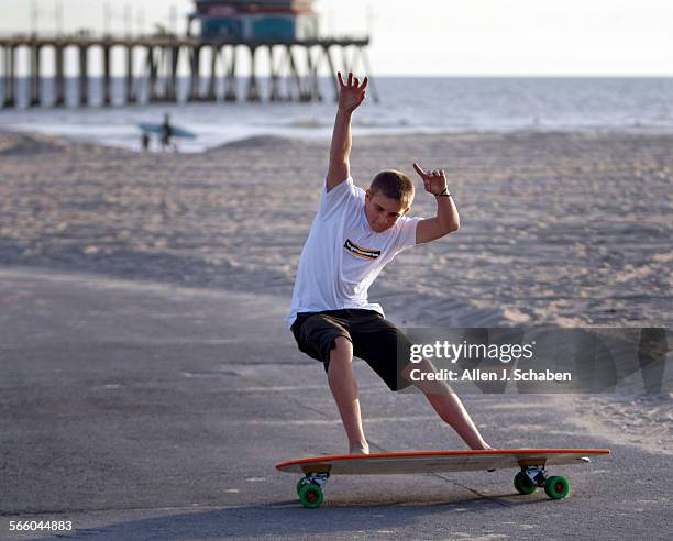 Jachin Hamborg does a tail slide, a move that complements his surfing style, on a 4'5" Fish Hamboard skateboard along the Huntington Beach bike path....