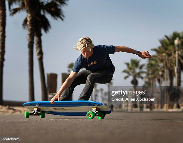 Gus Hamborg does a tail slide, a move that complements his surfing style, on a 6'8" long Hamboard longboard skateboard along the Huntington Beach...