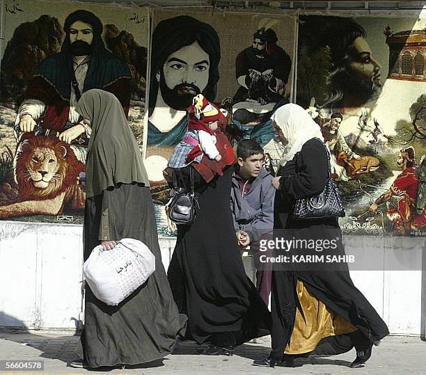 Iraqi women walk past carpets on display bearing the pictures of Imam Ali , cousin of Prophet Mohammed, and his son Imam Hussein in Baghdad 17...