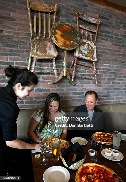 Jessenia Uvidia serves pizza to Kelli Paffenroth and Ron Roussell at Ecco, an Italian restaurant at the Camp, a hip mall in Costa Mesa.