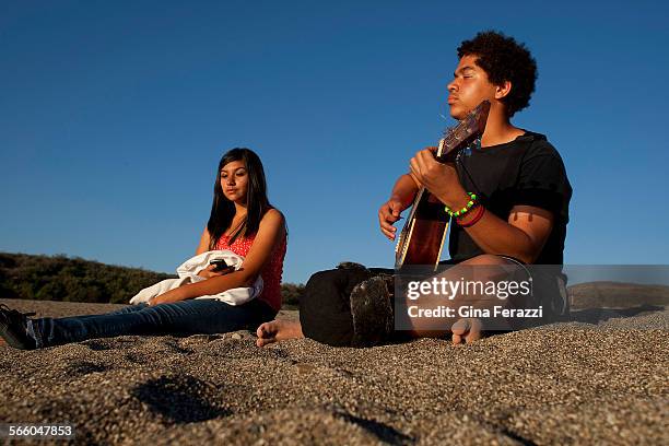 Ronnie Brown of Bakersfield enjoys the warm sun on his face and the golden sand on his feet while strumming his guitar with with his friend Maria...