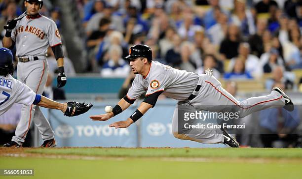 San Francisco Giants Travis Ishikawa scores on a wild pitch as Dodgers pitcher Joe Beimel can't get a glove on the ball to make the tag in the fifth...