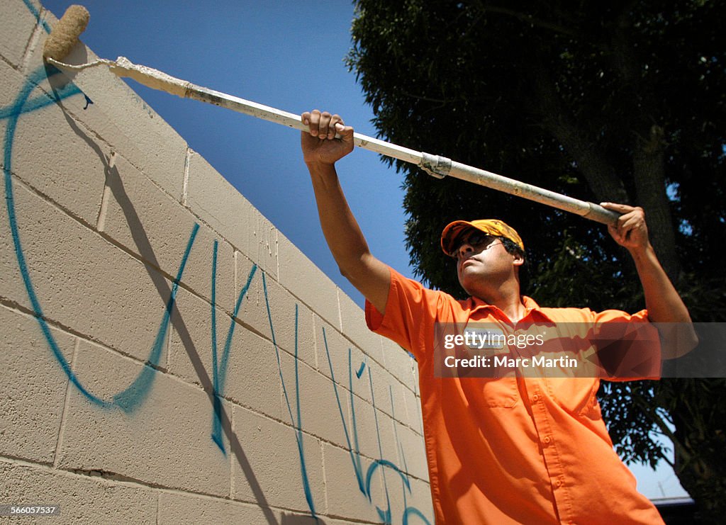 Steve Martin with the Stanton public works dept. paints over a graffiti covered cinder block wall i