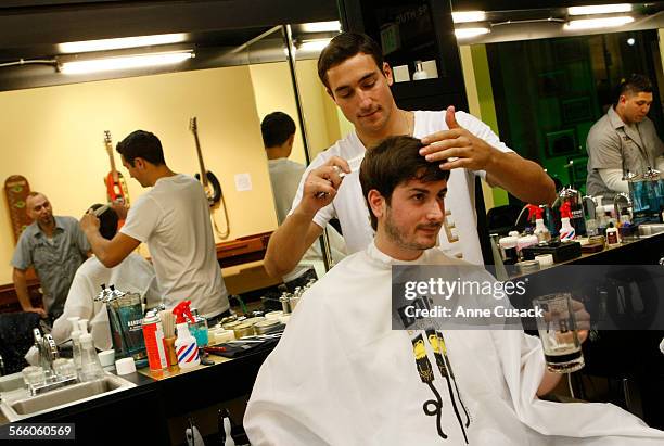 Nick Pasqua cuts the hair of Aaron Lippman, as he drinks a rootbeer, at a new Barber shop in downtown Los Angeles called Bolt and opened by a 46 year...
