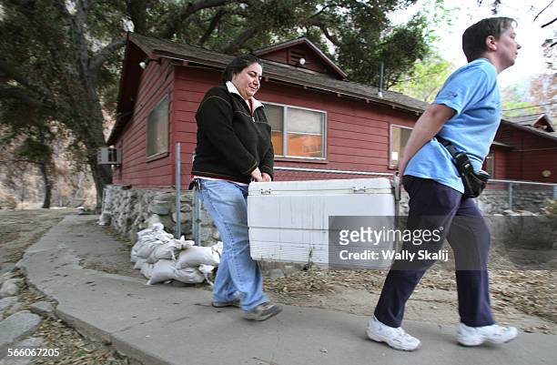 Bronwen Aker, left, receives help from friend Diane Wright while evacuating from her house for the winter in Big Tujunga Monday.
