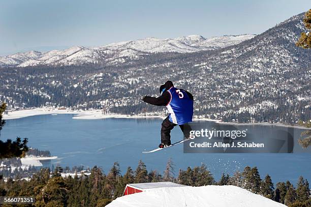 Snowboarder soars over a jump and box with a view of snowcovered San Bernadino Mountains and Big Bear Lake. Thousands of Southern Californians...