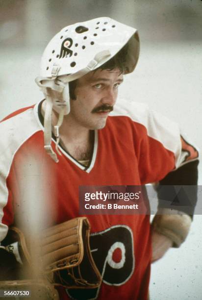 Canadian professional goalie Bernie Parent of the Philadephia Flyers stands on the ice with his face mask flipped up on his head during a 1970s NHL...