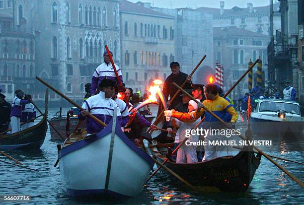 Italian torchbearers hold the Olympic flame on a gondola along Canal Grande in Venice, 17 January 2006. The Olympic torch will tour 140 Italian...
