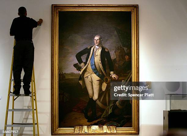 Worker uses a ladder to work near a full length portrait of former U.S. President George Washington, by Charles Wilson Peale, at Christie's auction...