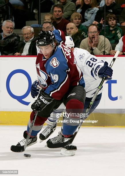 Joe Sakic of the Colorado Avalanche controls the puck in front of Tie Domi of the Toronto Maple Leafs during NHL action on January 17, 2006 at the...