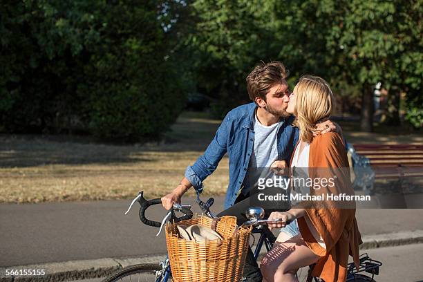 couple kissing and cycling in park - london bikes stock pictures, royalty-free photos & images